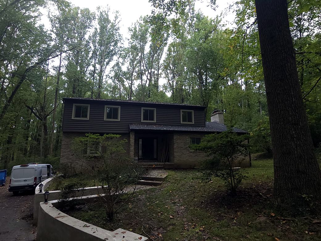Same home with dark siding and a new curved retaining wall along the drive